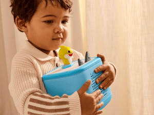 child holding a toniebox 2 with a baby shark tonie on top