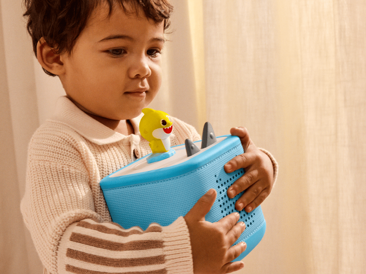 child holding a toniebox 2 with a baby shark tonie on top