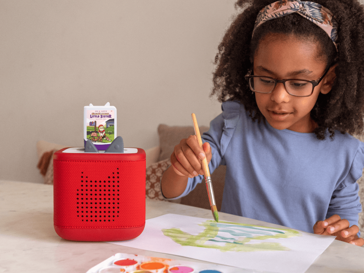 child painting and listening to Baby-Sitters Little Sister Book Tonies on a red toniebox 2