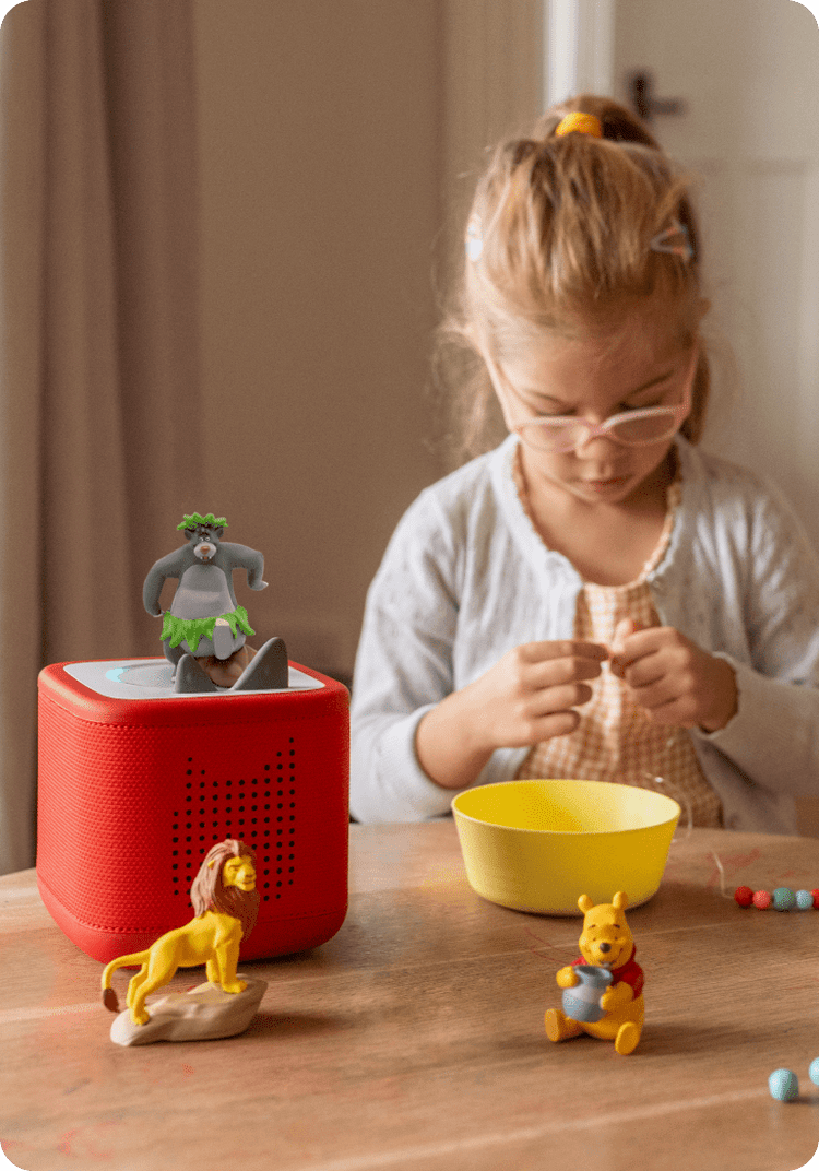 Child during arts and crafts listening to Disney Tonies on a red Toniebox 2