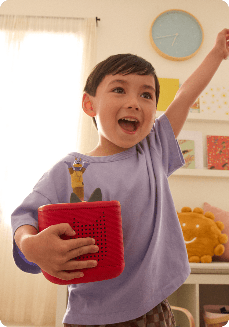 Childing holding a red Toniebox 2 while listening to the Doggyland Tonie