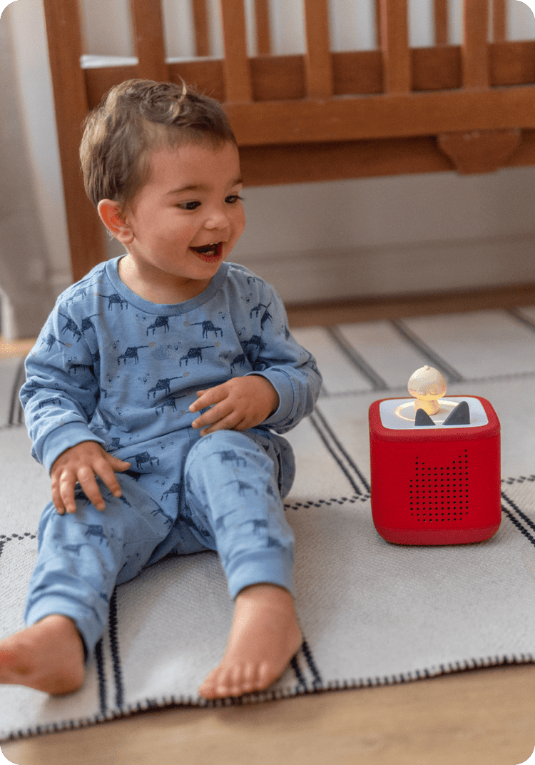 Child in pajamas listening to Sleepy Friends Duck on a red Toniebox 2