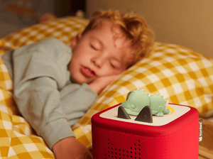 child sleeping in the backgroun with a Doudou Croco tonie on a red toniebox 2