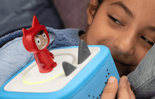 child holding a blue Toniebox 2 with a Creative Tonie on top