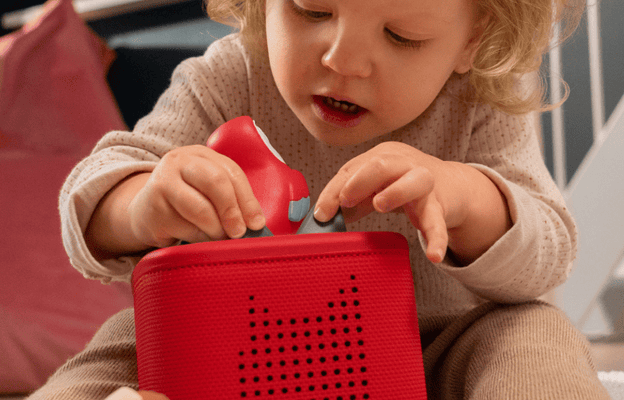 Young child playing on the floor with a red Toniebox 2 and Jungle Set My First Tonies