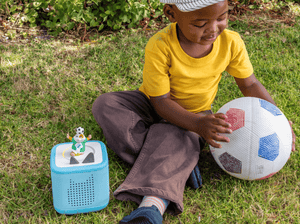 child playing with soccer ball and All-Star Animals-The Golden Whistle Games Soccer Tonie with a blue toniebox 2