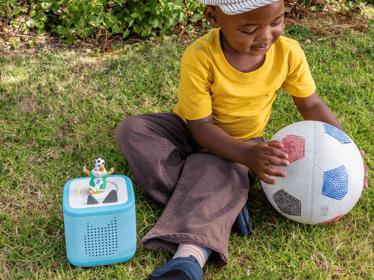 child playing with soccer ball and All-Star Animals-The Golden Whistle Games Soccer Tonie with a blue toniebox 2