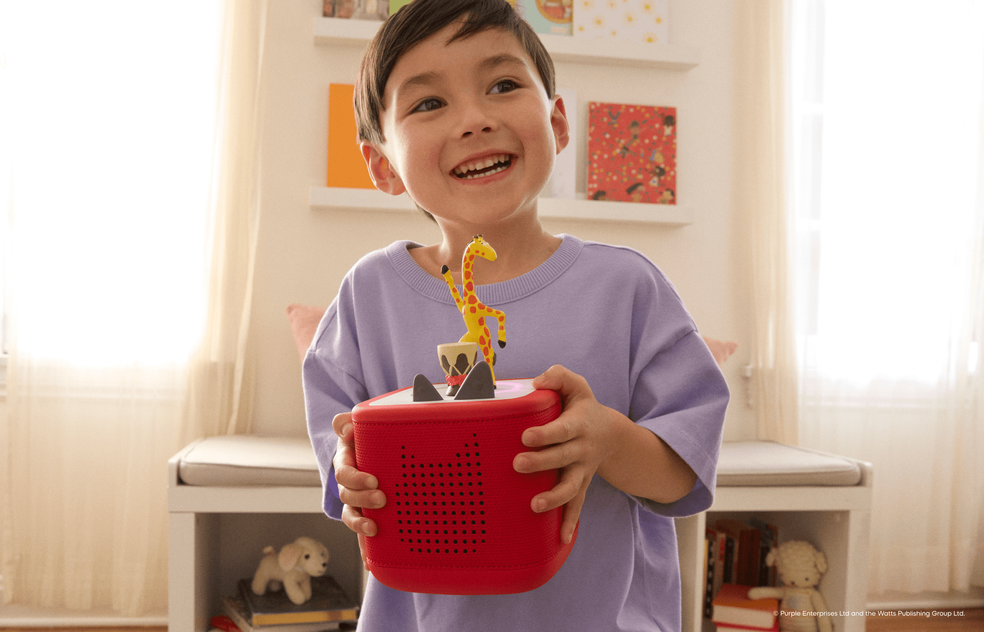 child holding a red Toniebox with the Giraffes Can't Dance Tonie on it