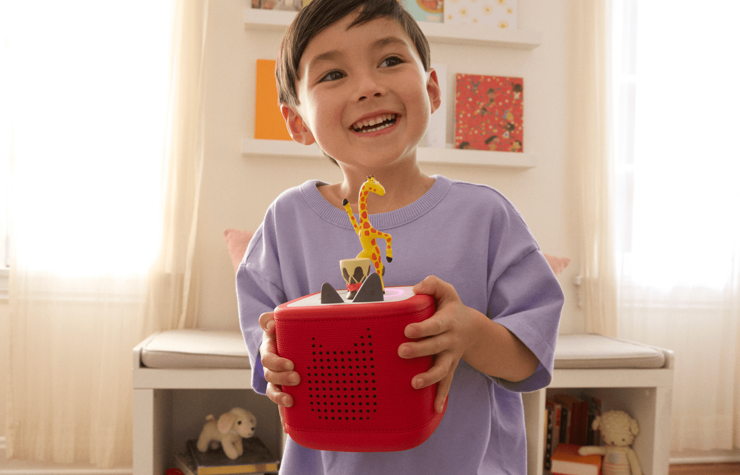 child holding a red Toniebox with the Giraffes Can't Dance Tonie on it