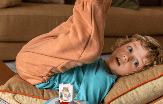 child laying on a wooden bench listening to an audiobook for kids on a blue Toniebox 2