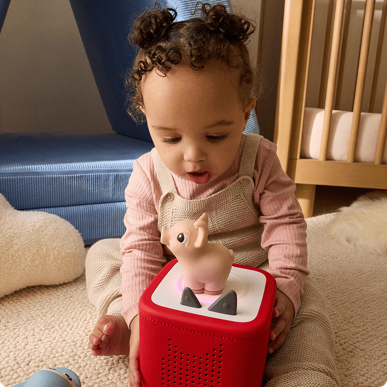 young child listening to Pig My First Tonie on a red Toniebox 2