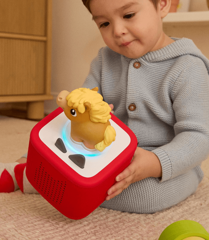 child holding a red Toniebox 2 while listening to the Horse My First Tonie