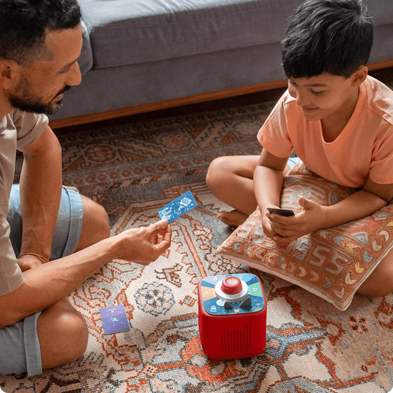 Father and son play Tonieplay game on red Toniebox 2 together