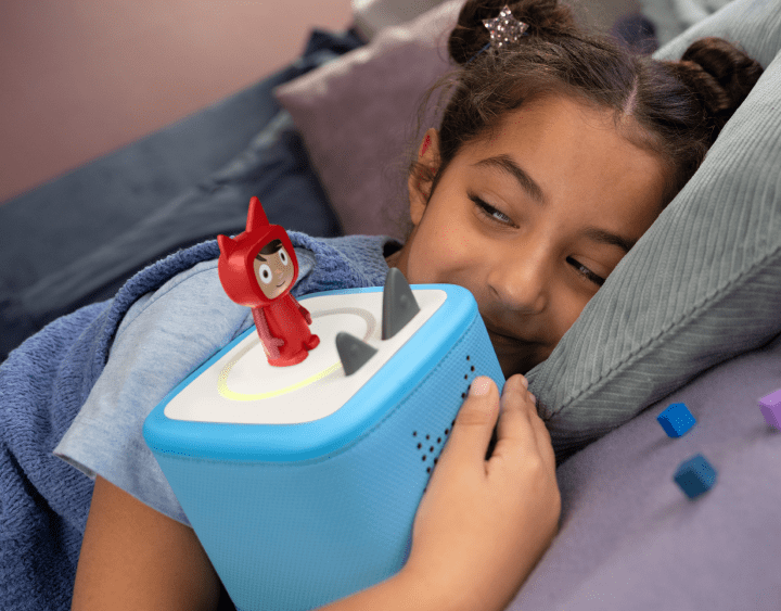 Child holding a blue Toniebox 2 with a Creative Tonie on top