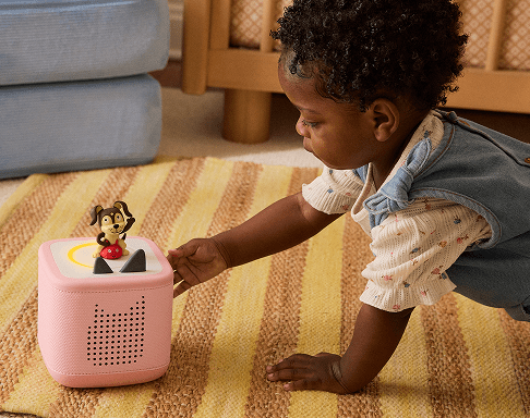 little girl next to a pink Toniebox 2 with Playtime Puppy Tonie on top